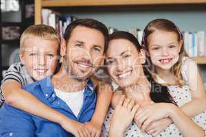 Portrait of cheerful family against shelf in living room