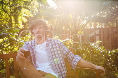 Man sitting on a bench with a glass of red wine