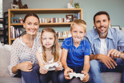 Smiling children playing video games with parents