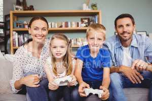 Smiling children playing video games with parents