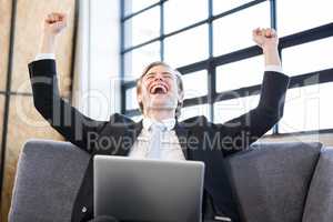 Businessman raising hands with excitement in front of laptop