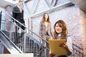 Businesswoman standing near staircase with documents