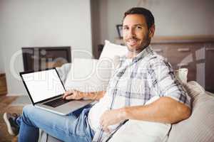 Portrait of smiling man using laptop at home