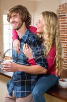 Cute couple cuddling with girlfriend sitting on the counter