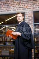 Lawyer standing near library with law book