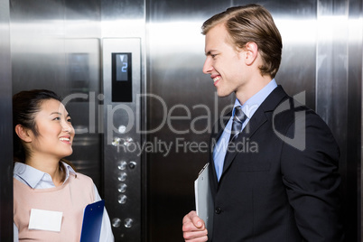 Businessman and businesswoman standing in an elevator