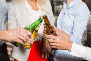 Close up of friends toasting with bottles of beer