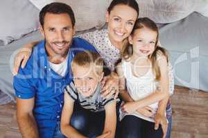 Portrait of cheerful family sitting by sofa