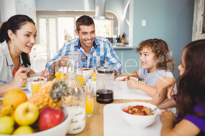 Cheerful family eating breakfast at table