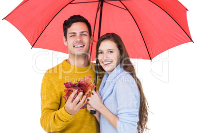 Happy couple under an umbrella holding leaves