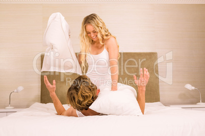 Cute couple pillow fighting on their bed