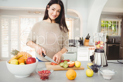 Portrait of happy woman cutting fruits