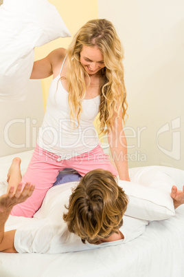 Cute couple pillow fighting on their bed