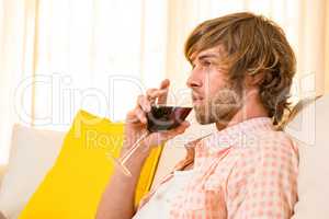 Handsome man enjoying a glass of wine on the couch