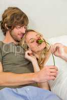 Cute couple cuddling with girlfriend smelling a rose