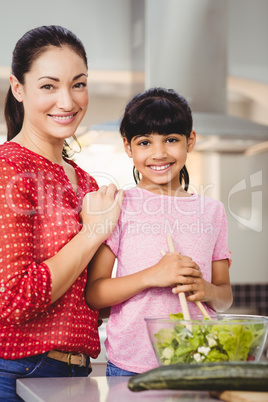 Portrait of smiling mother and daughter preparing salad