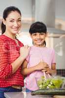 Portrait of smiling mother and daughter preparing salad