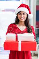Portrait of woman in Christmas attire standing with Christmas gi
