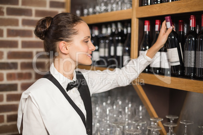 Barmaid taking bottle out of shelf