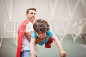 Low angle view of father holding son wearing superhero costume