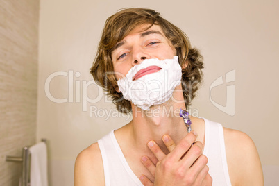 Handsome man shaving in the bathroom