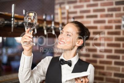 Barmaid looking at a wine glass