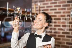 Barmaid looking at a wine glass