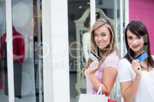 Portrait of happy women showing their credit cards in mall