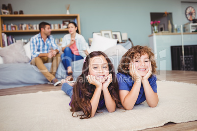 Children lying on carpet while parents sitting in background