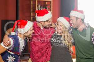 Friends wearing Christmas hats looking at each other