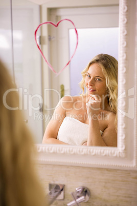 Beautiful blonde looking a big heart on mirror