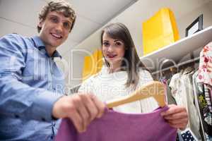 Portrait of couple selecting a dress while shopping for clothes