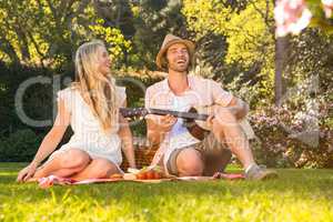 Happy couple having a picnic and playing guitar