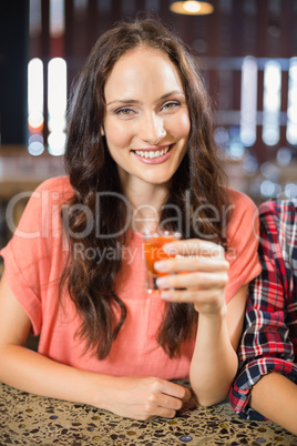 Woman looking at camera with shot in hand