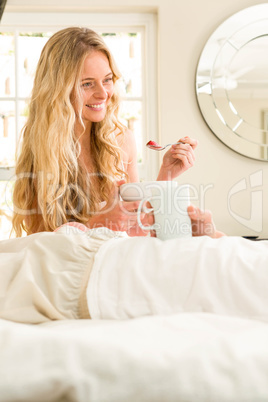 Cute couple eating cereals and lying in bed