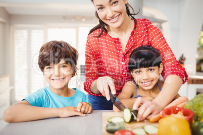 Happy woman with children chopping vegetables at home