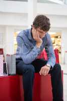 Tired man sitting in shopping mall