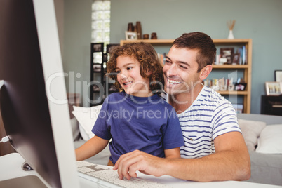 Happy father and son using computer at home