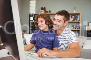 Happy father and son using computer at home