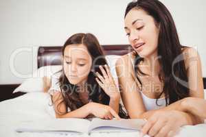 Close-up of mother and daughter reading book