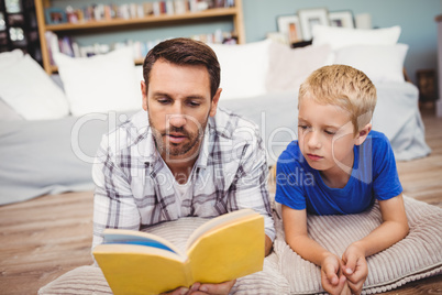 Close-up of father and son reading book at home