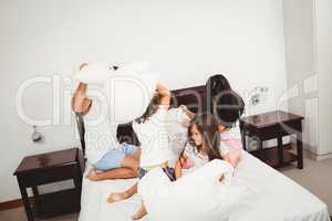 Family pillow fighting on bed