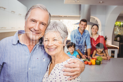 Portrait of senior couple with family preparing food in backgrou Portrait of senior couple with family preparing food in backgrou