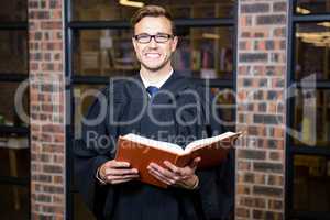 Lawyer standing near library with law book