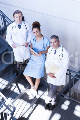 Portrait of doctors standing on staircase with document