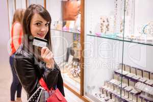 Portrait of beautiful woman showing her credit card in a jeweler