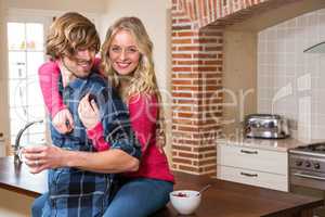 Cute couple cuddling with girlfriend sitting on the counter