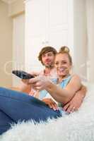 Cute couple watching tv and using remote on the couch