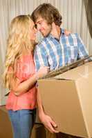 Happy couple embracing with moving box