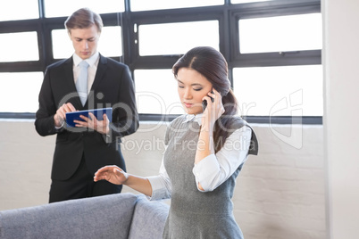 Businesswoman talking on smartphone and businessman using digita